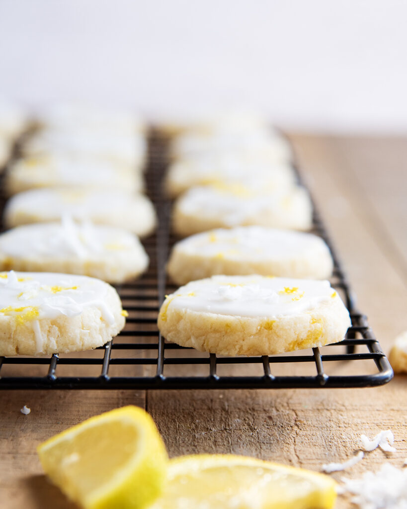 Rows of coconut lemon shortbread cookies on a black wire rack.