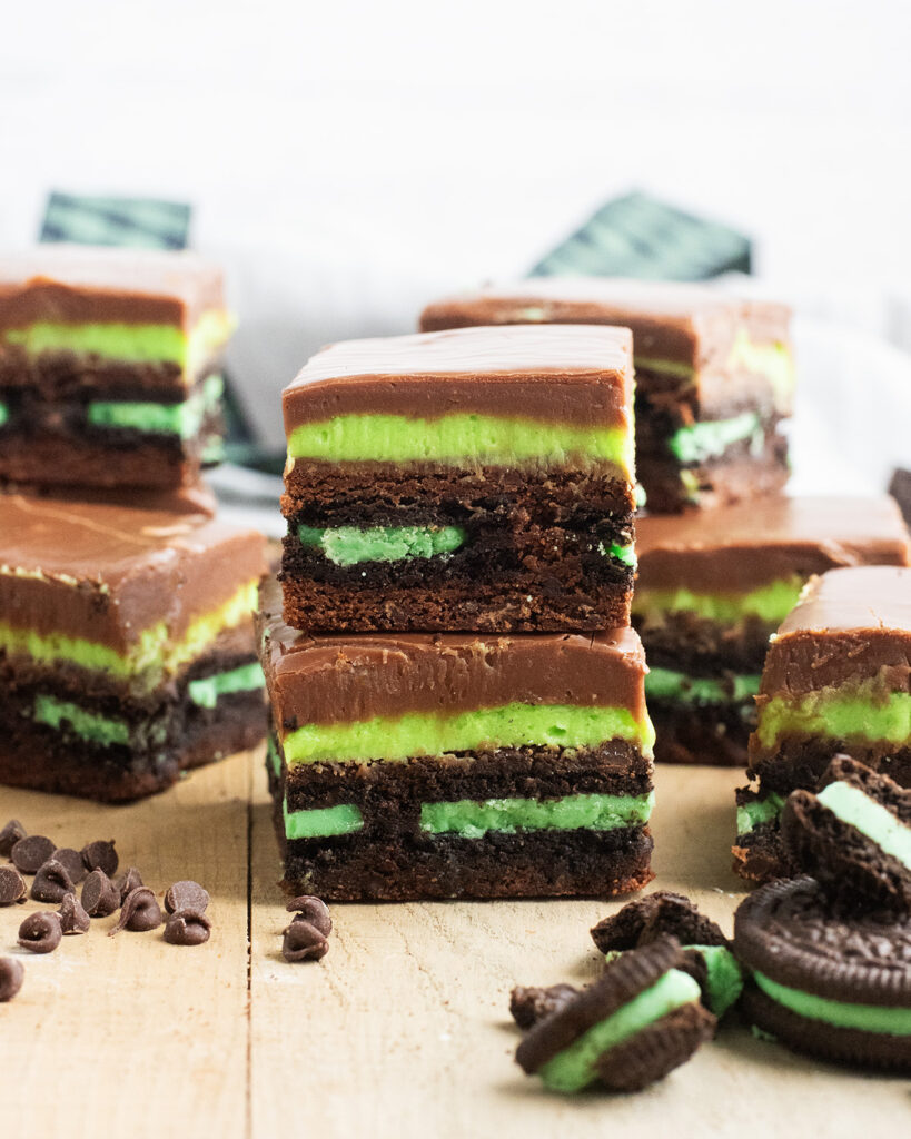 A stack of two Mint Oreo Brownies, with green mint frosting, and chocolate fudge on top.