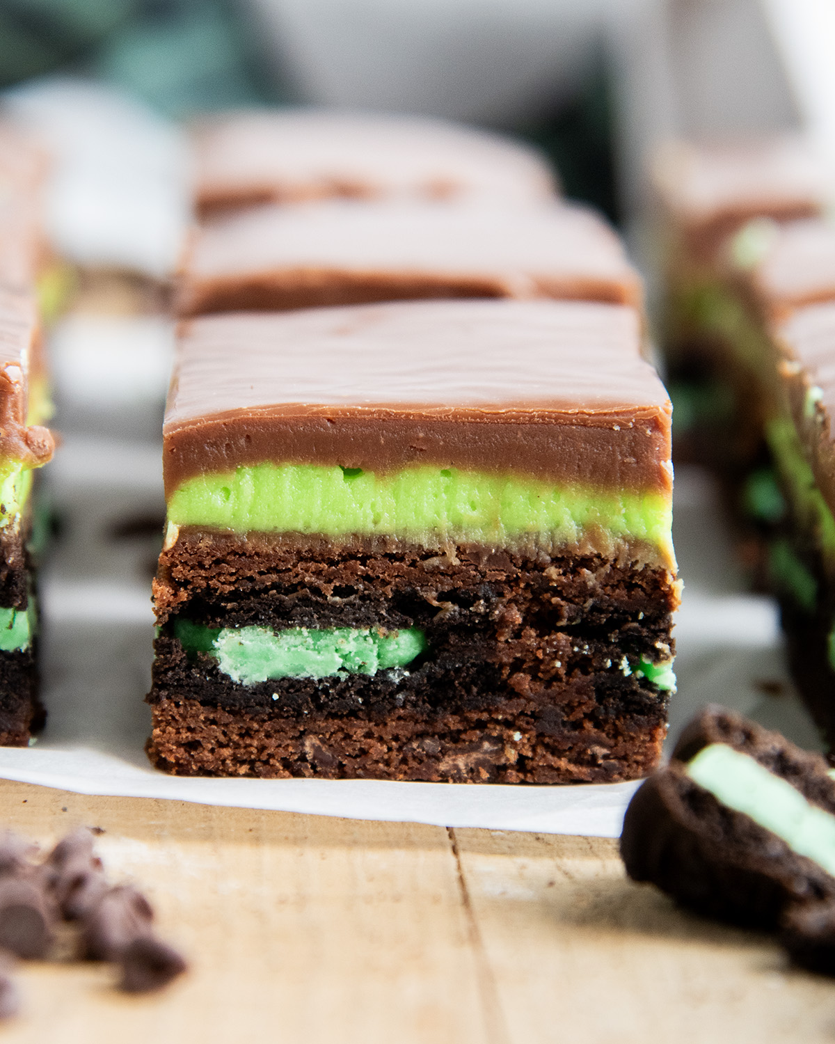 A Mint Oreo Brownie with a mint oreo in the middle of a brownie topped with a green frosting and chocolate fudge.