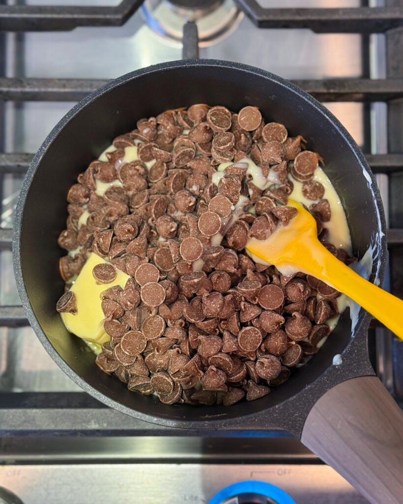 A pot of butter, sweetened condensed milk and chocolate chips on the stove.