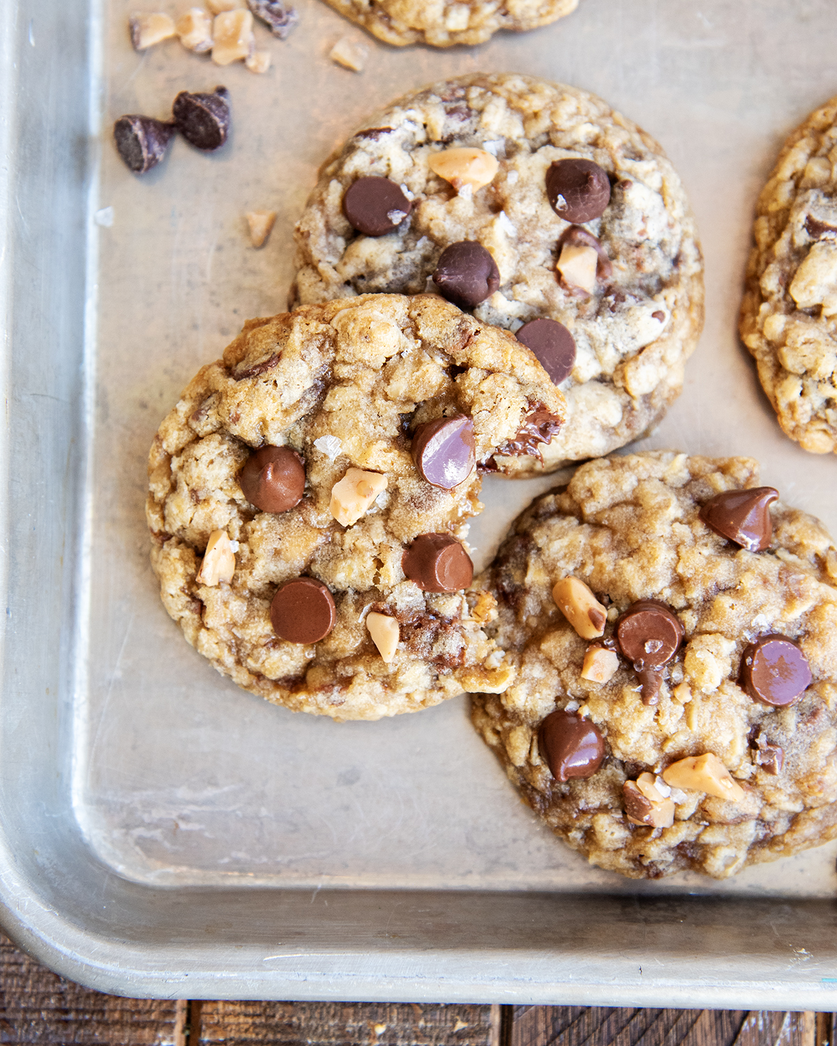 A pan of oatmeal toffee cookies, one has a bite out of it.