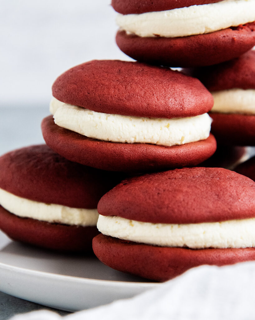 A stack of red velvet whoopie pies on a plate.