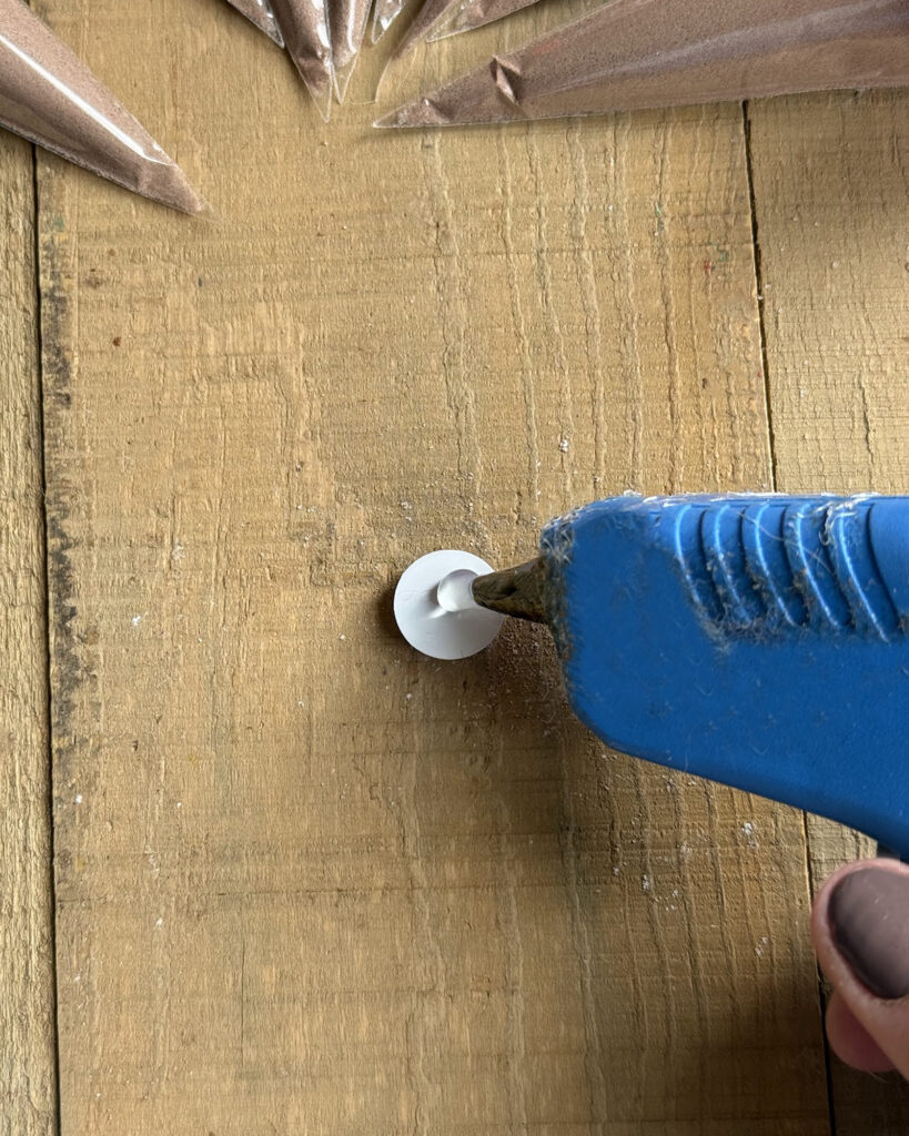 A hot glue gun putting a dop on the back of a googly eye.