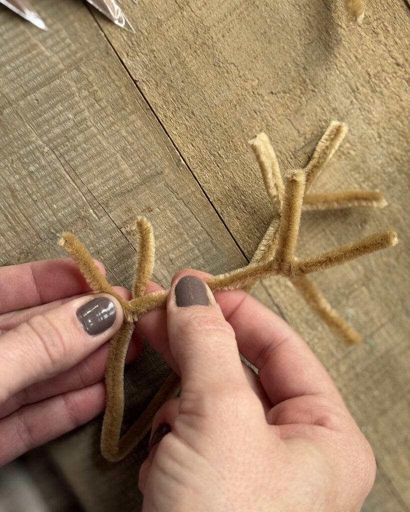 Two hands making antlers out of pipe cleaners.