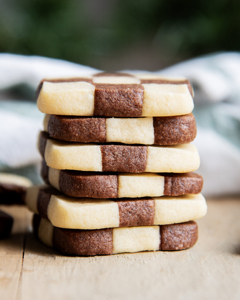 A stack of checkerboard cookies on a wooden table.