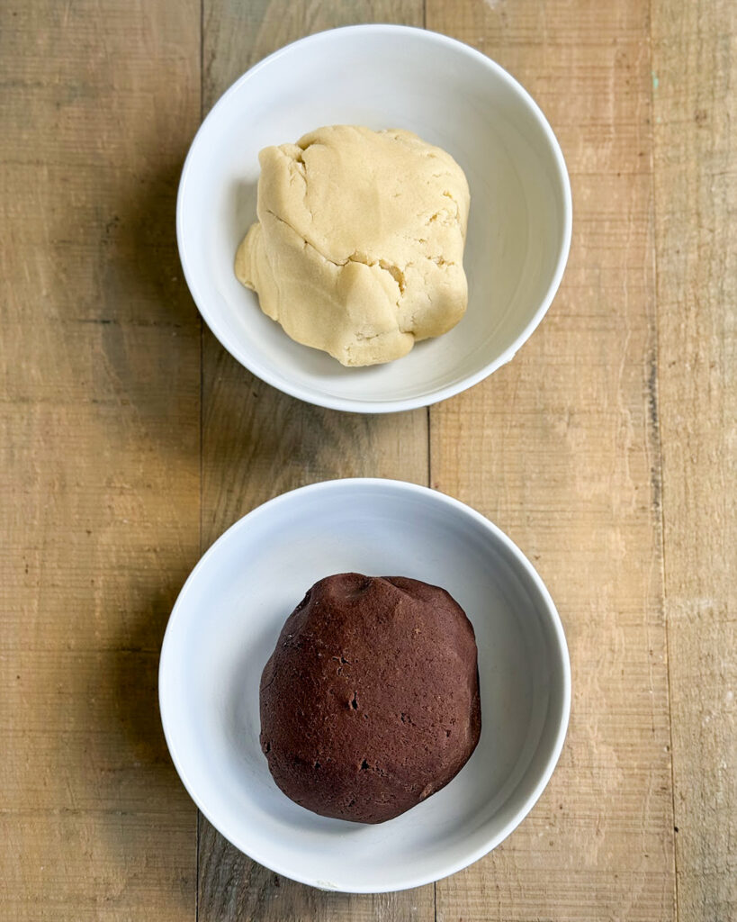 A bowl of vanilla cookie dough, and a bowl of chocolate cookie dough.