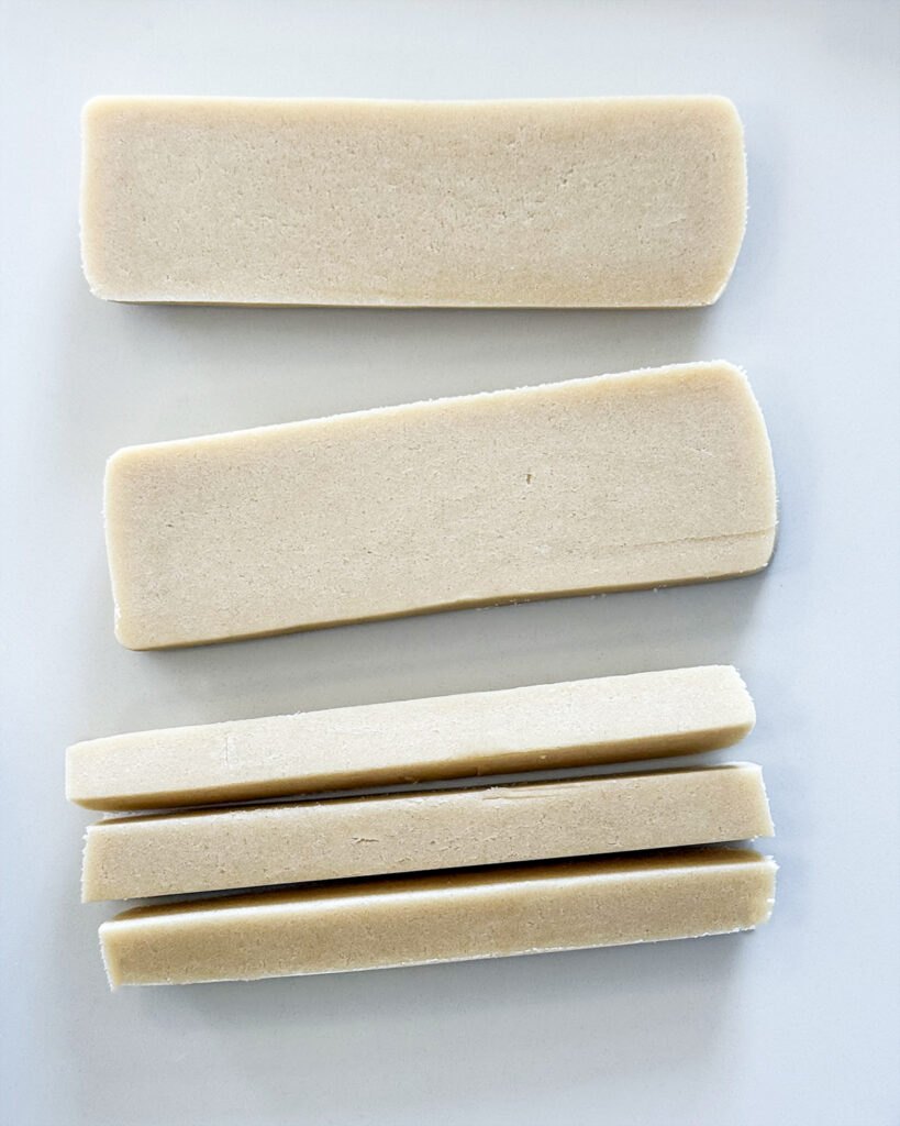 Sliced sugar cookie dough on a counter top to make checkerboard cookies.