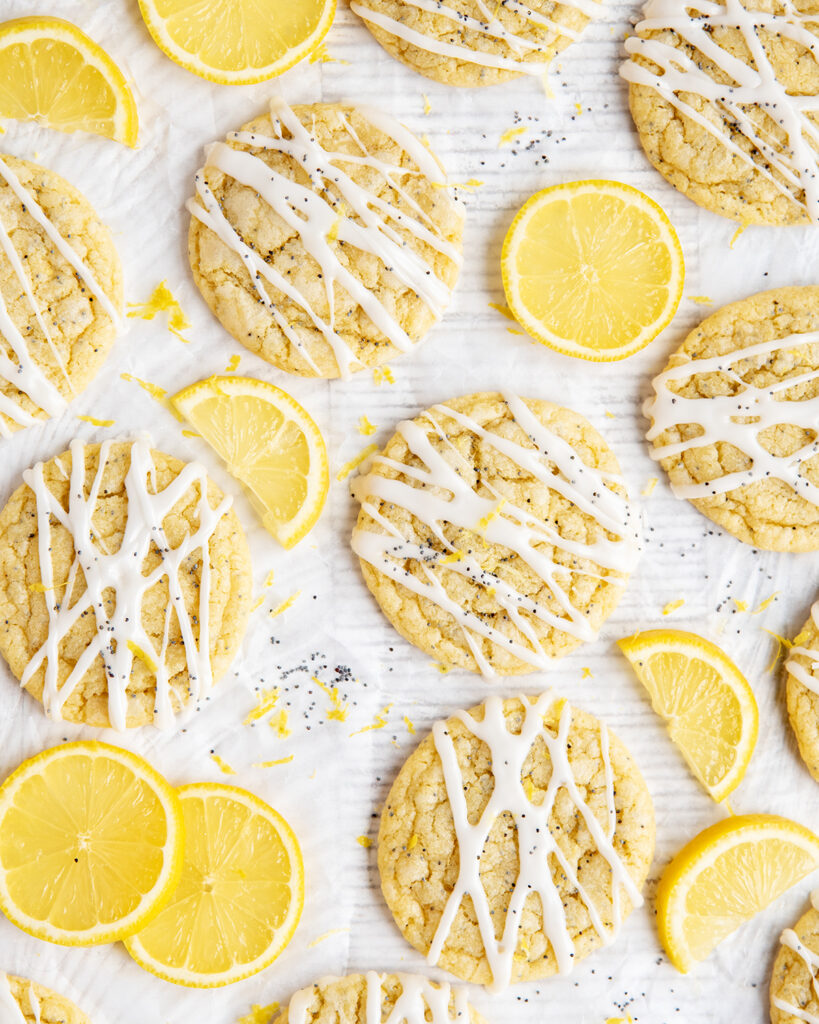 An above view of iced lemon poppy seed cookies next to slices of fresh lemon.