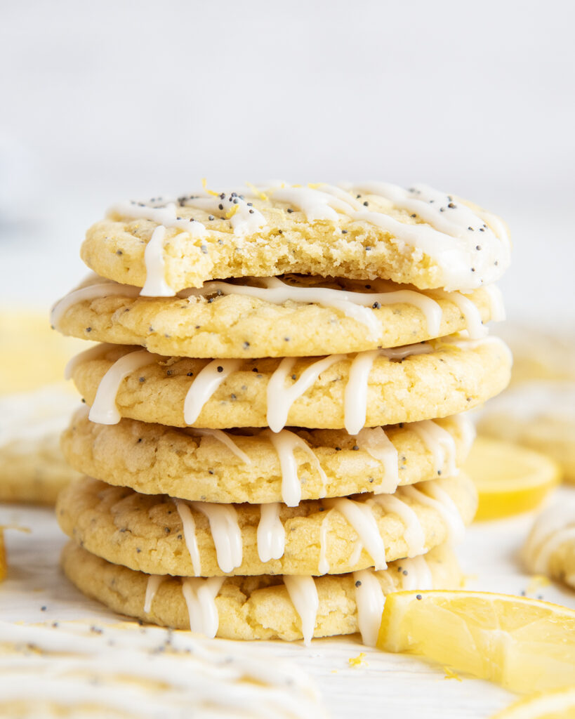 A stack of lemon poppy seed cookies with icing on top, with a bite out of the top cookie.