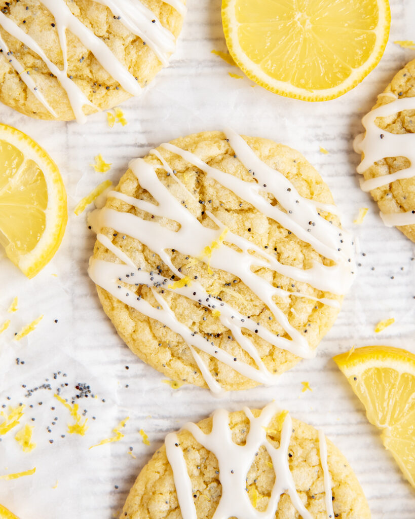 An above view of iced lemon poppy seed cookies next to slices of fresh lemon.