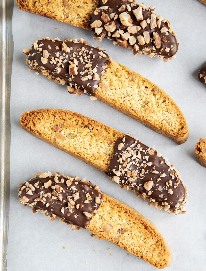 An above view of almond biscotti dipped half way in chocolate, and topped with chopped almonds.