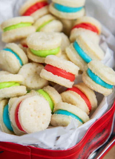 A close up of button sized creme wafer sandwich cookies, with red, green, and blue frosting in the middles.
