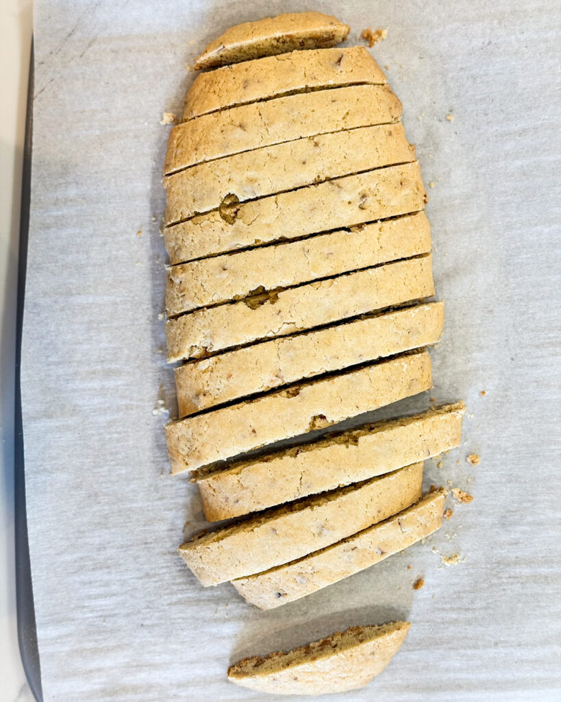 Sliced almond biscotti on a baking sheet before the second bake.