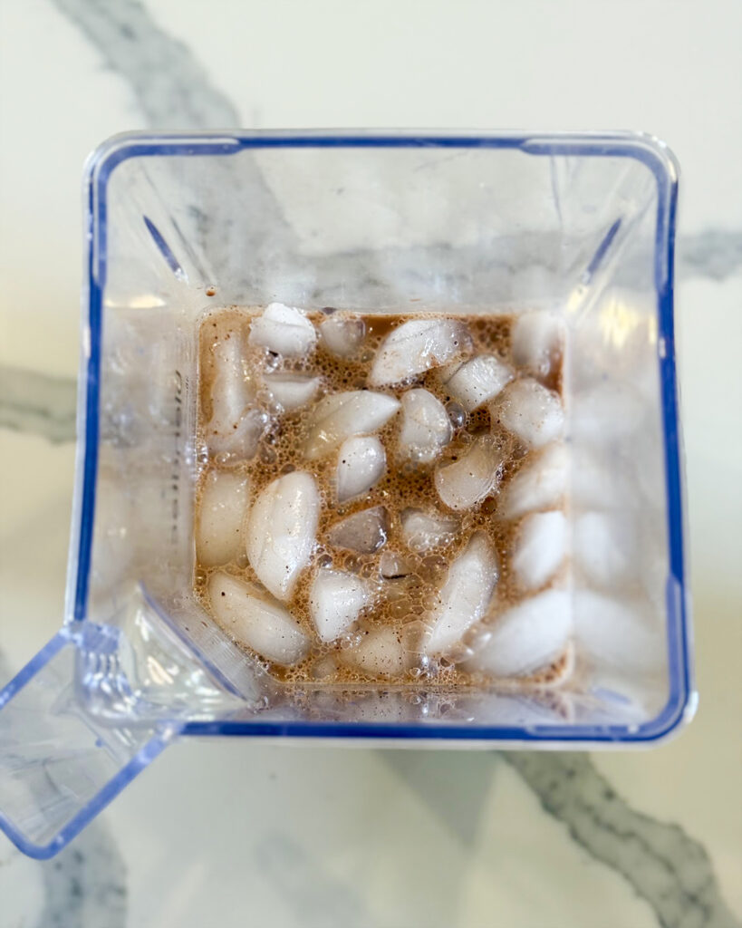 A chocolate milk mixture and ice in a blender.