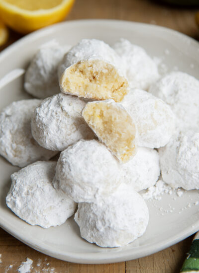 A plate of lemon snowball cookies, with two halves of a cookie showing the middle.