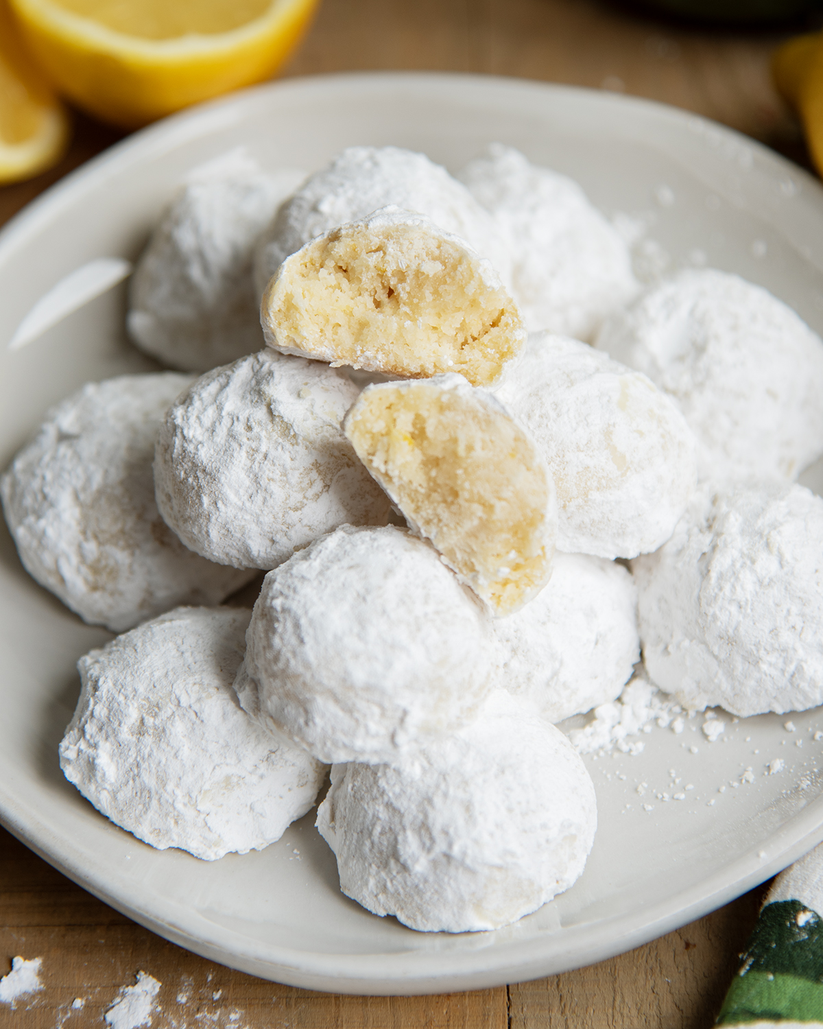 A plate of lemon snowball cookies, with two halves of a cookie showing the middle.