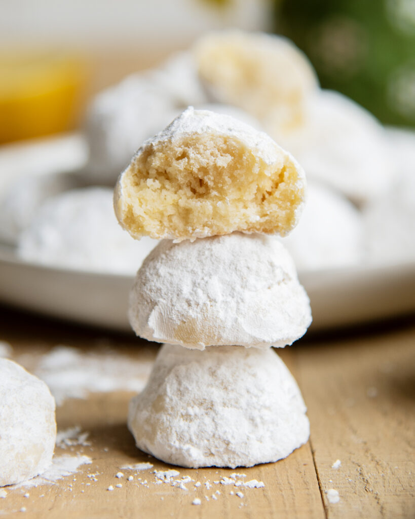 A stack of three lemon snowball cookies, and the top cookie is opened showing the center.