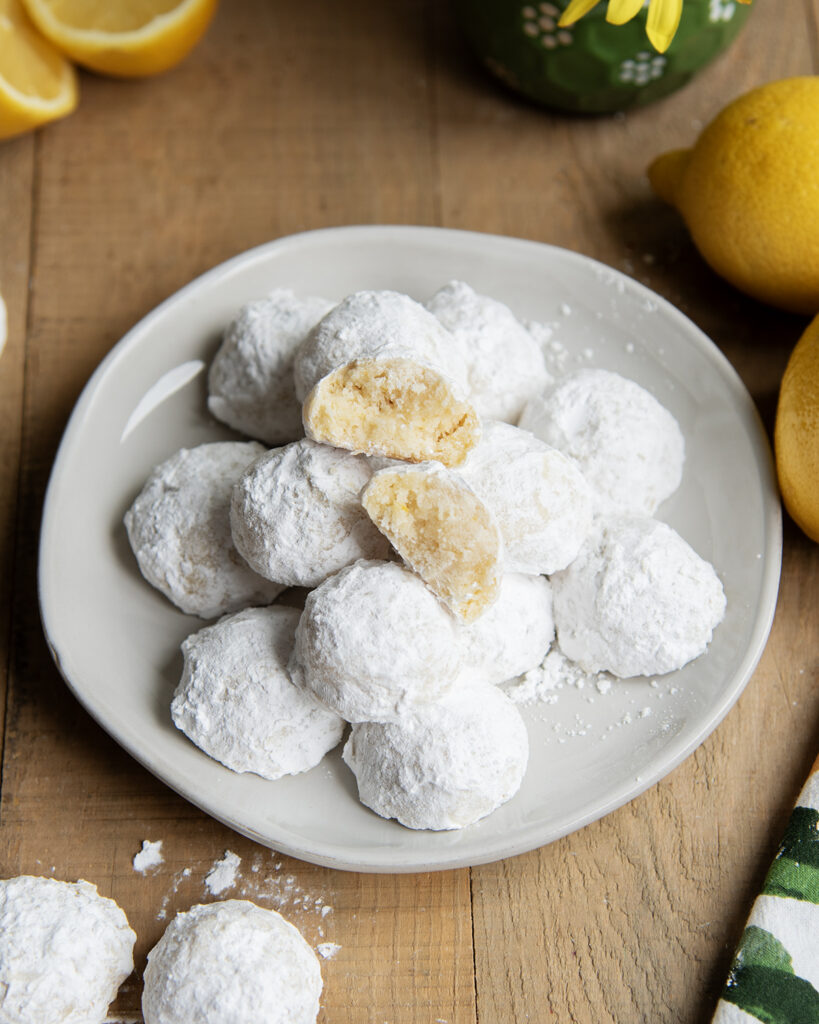 A plate of lemon snowball cookies, with two halves of a cookie showing the middle.