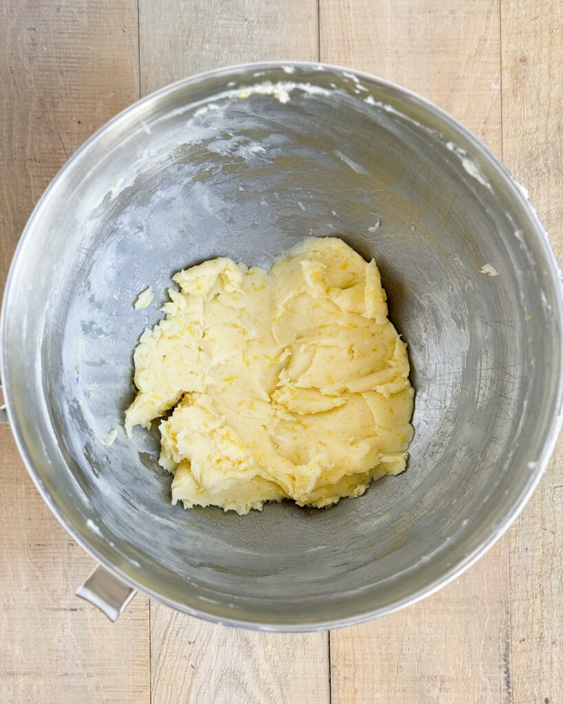 A bowl of creamed butter, powdered sugar, and lemon zest.