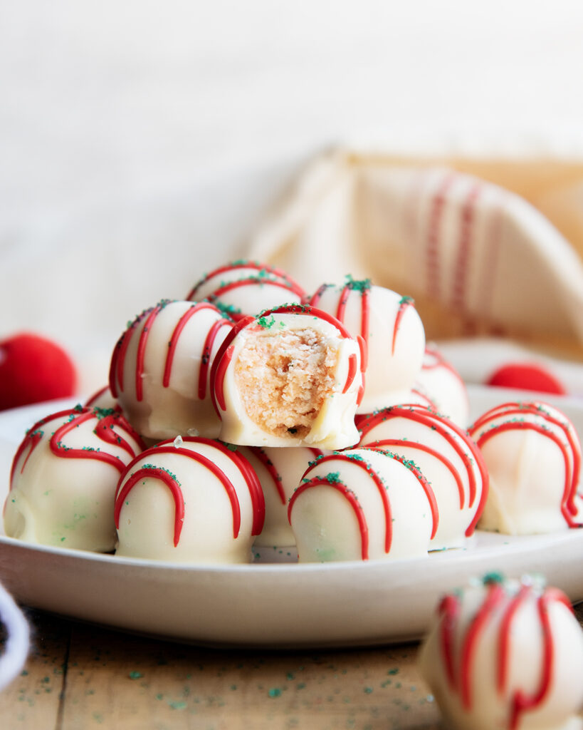 A plate of Little Christmas Tree Cake Balls in a pile, and one has a bite out of it. 