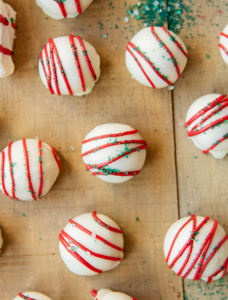 An above view of White Chocolate coated truffles drizzled with red candy and topped with green sprinkles.