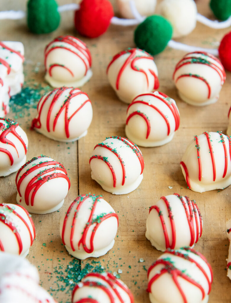 Little Debbie Christmas Tree Truffles on a wooden board dipped in white chocolate and drizzled with red candy melts.