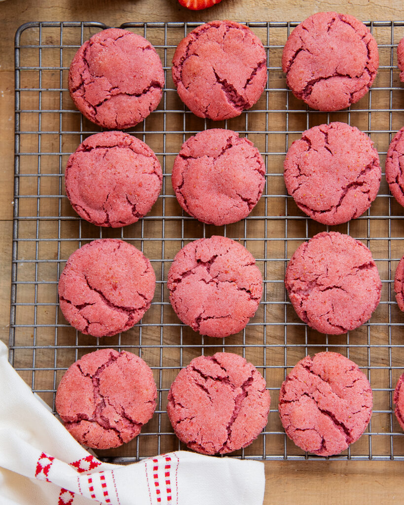 An above view of pink strawberry sugar cookies on a cooling rack.