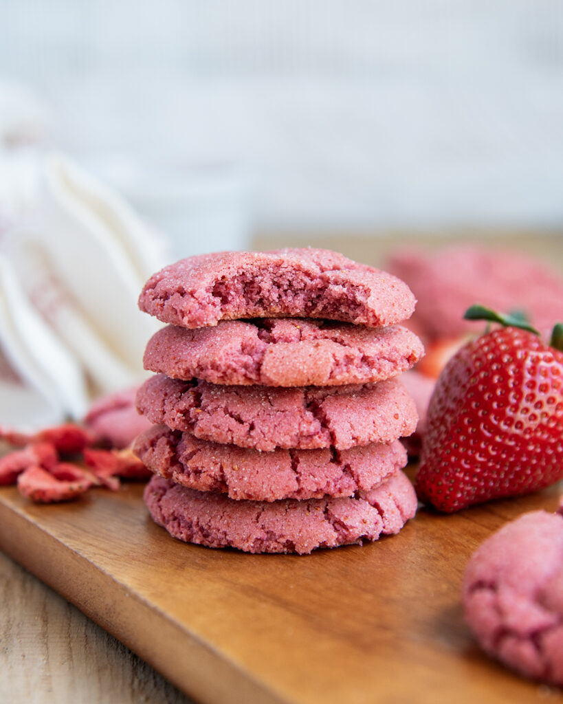A stack of strawberry sugar cookies, and the top as a bite out of it.