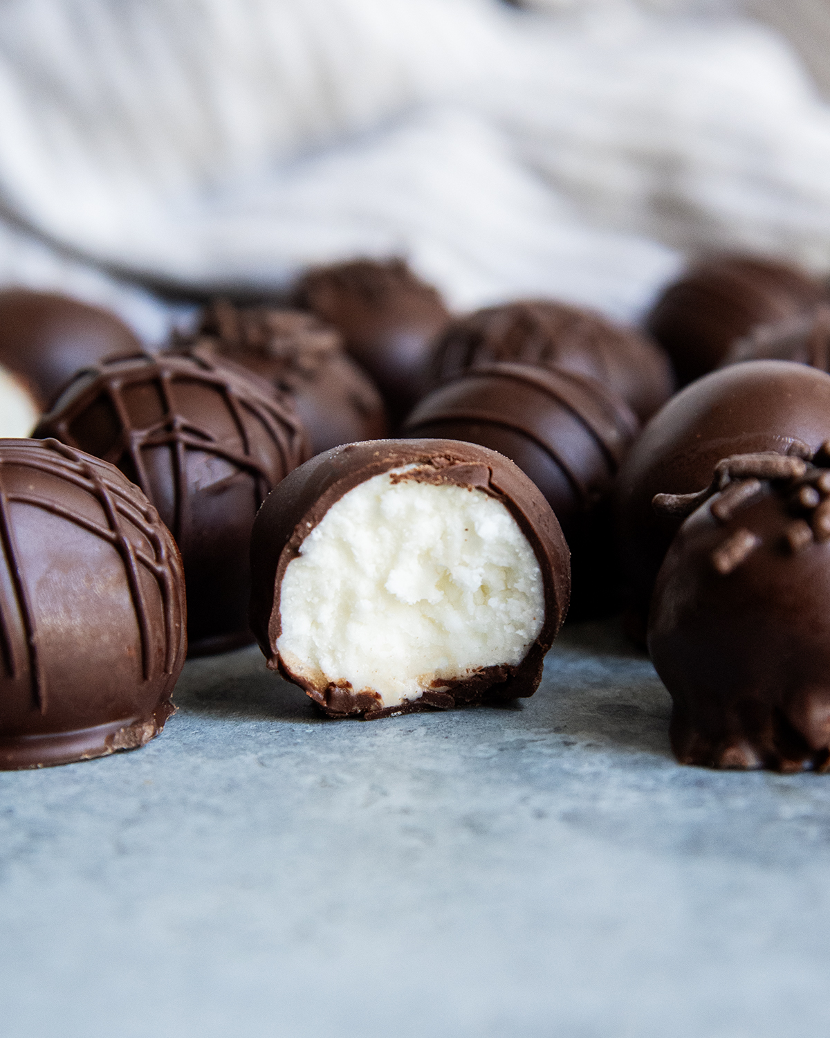 Chocolate coated Buttercream candies on a counter top, and one is showing the buttercream filling in the middle.