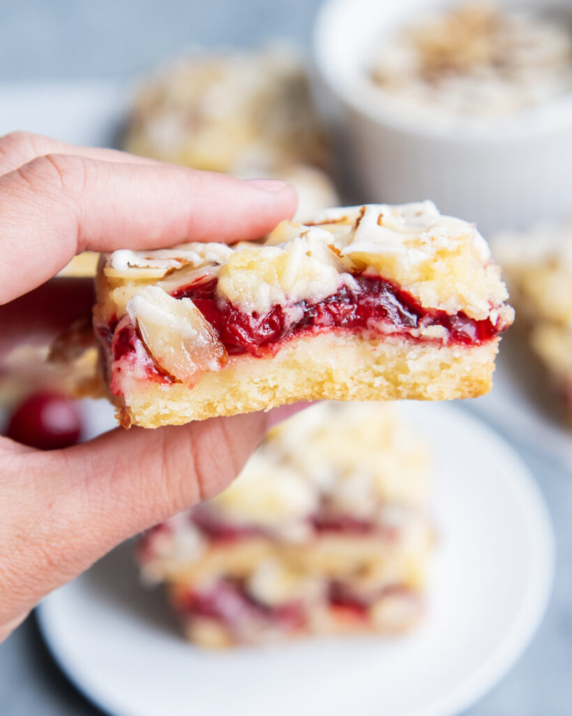 An almond and cherry cookie bar in a hand.