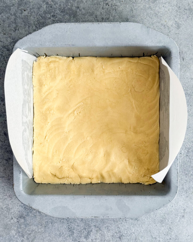 Cookie dough pressed into a square pan.