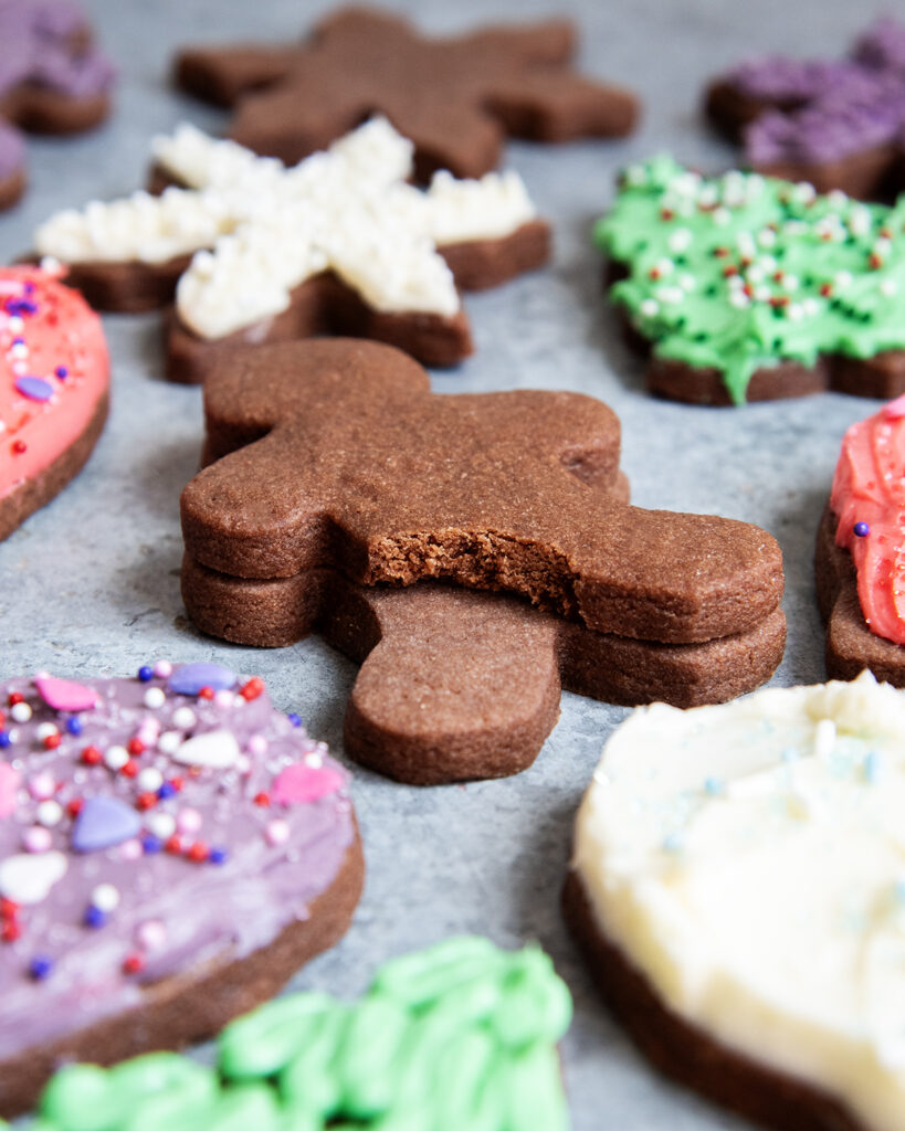 A stack of two chocolate cut out gingerbread men, and one has a bite out of it.