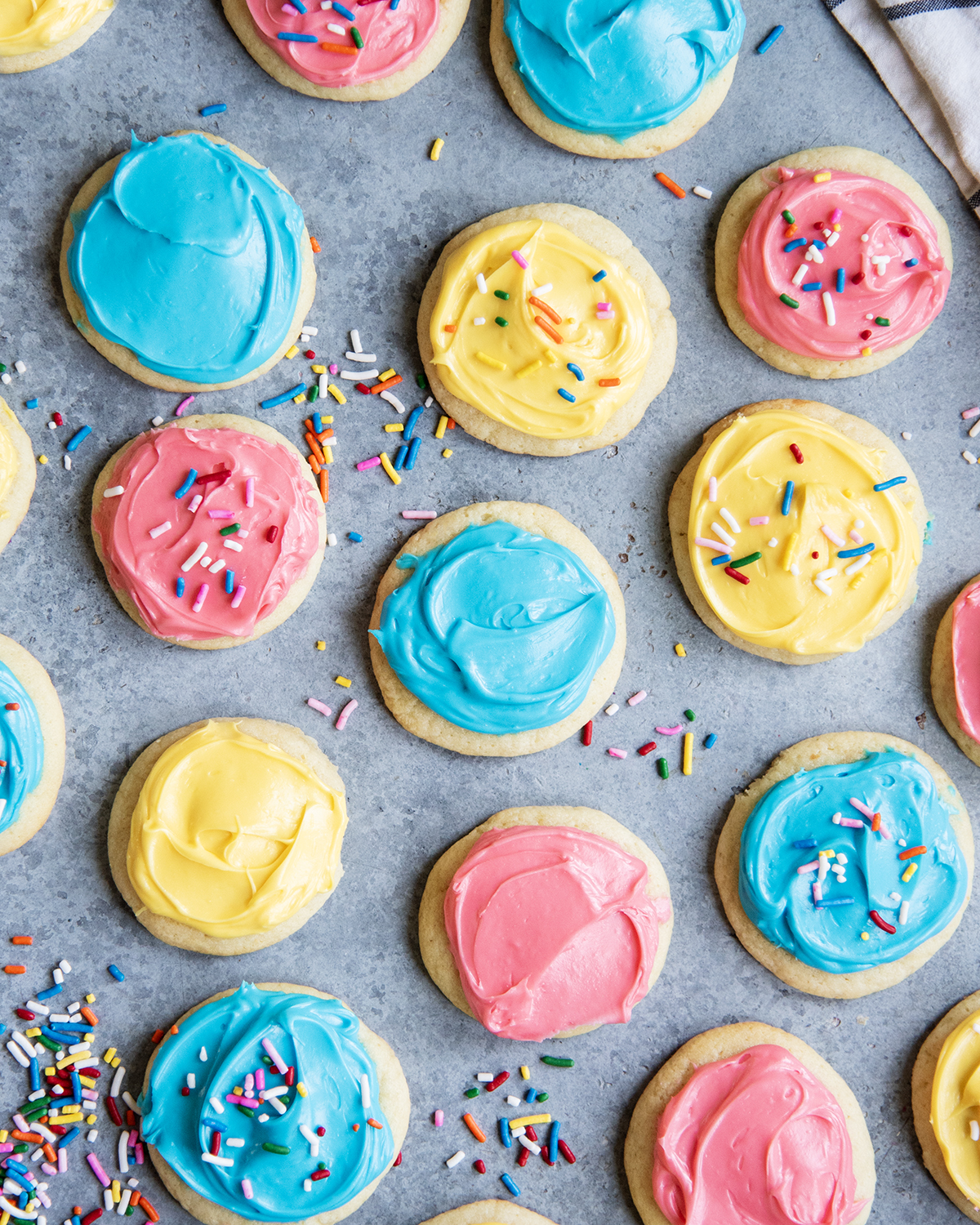 An above view of pink, yellow, and blue frosted sour cream sugar cookies.