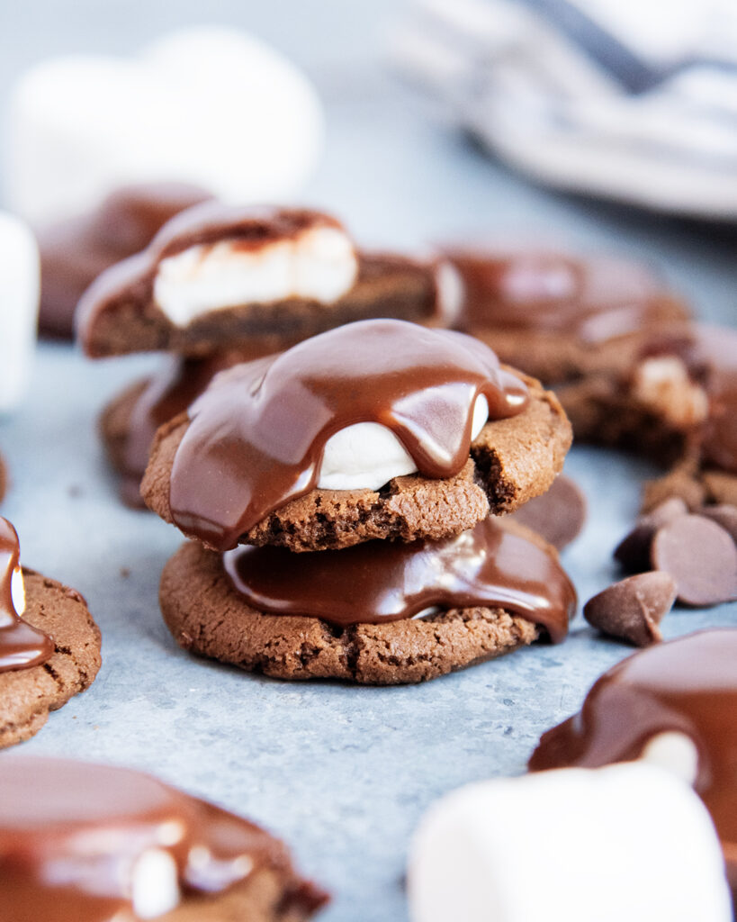 A stack of two chocolate cookies topped with a marshmallow, and chocolate ganache.
