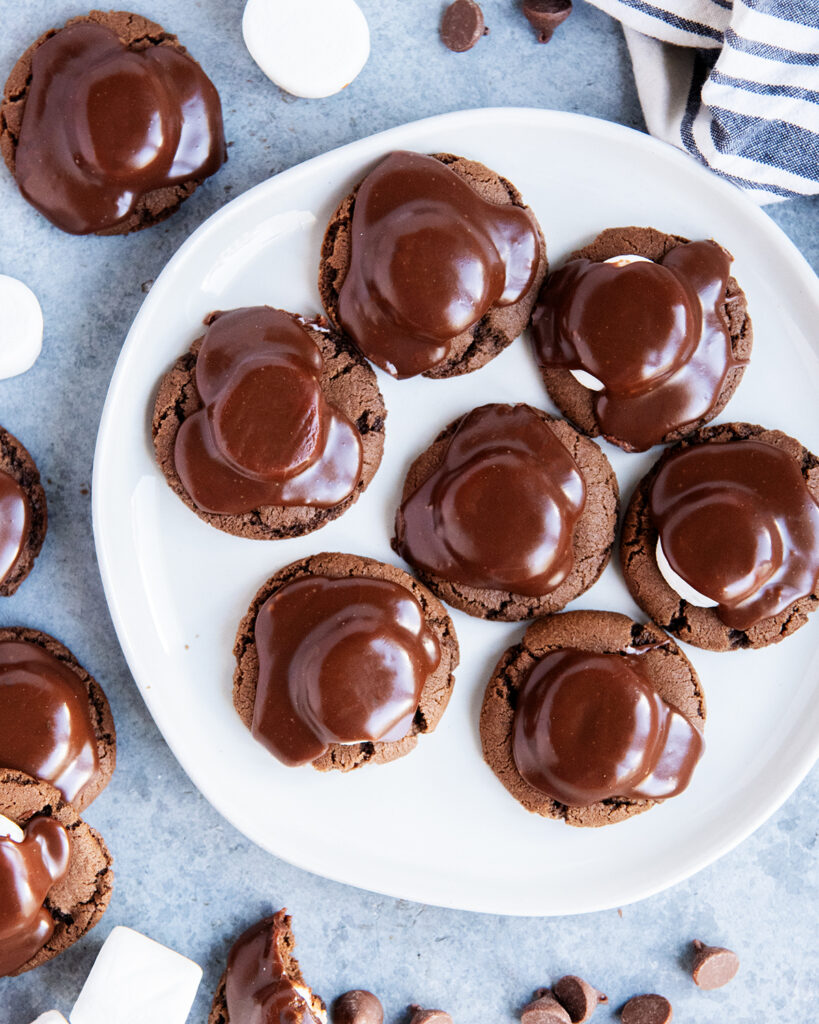 An above view of a plate of chocolate cookies topped with chocolate ganache.