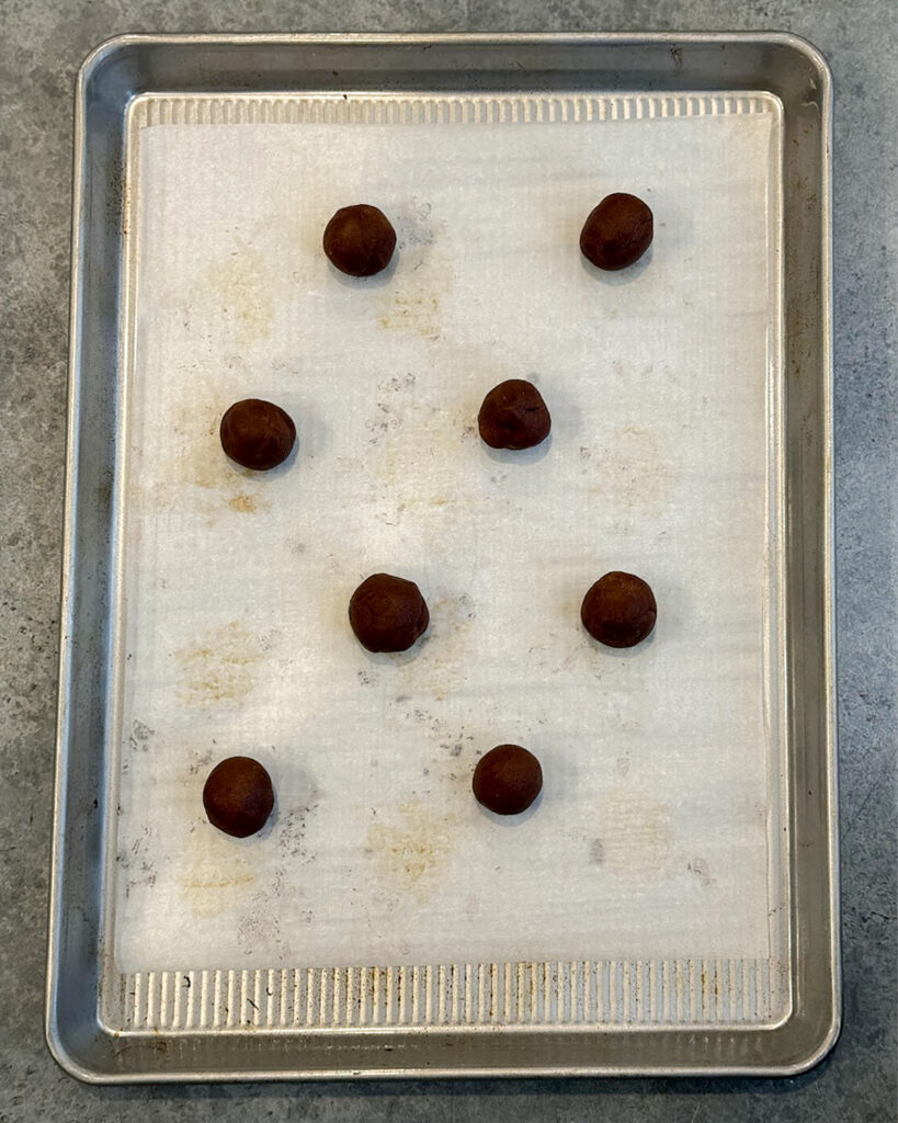 Chocolate cookie dough balls on a baking tray.