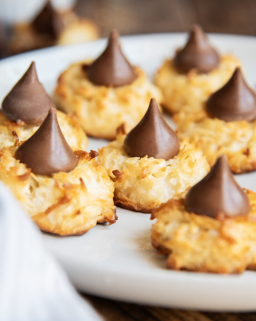 A plate of coconut macaroon cookies topped with hershey kisses. 