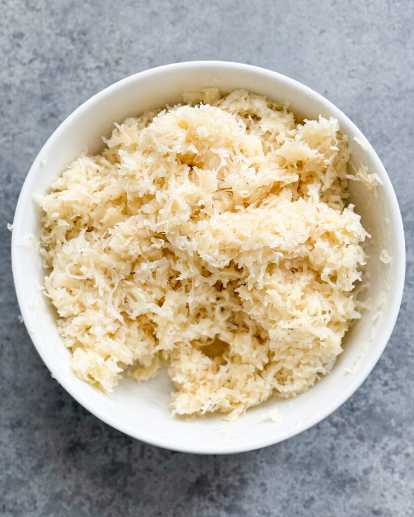 Sweetened condensed milk mixed with shredded coconut in a bowl.