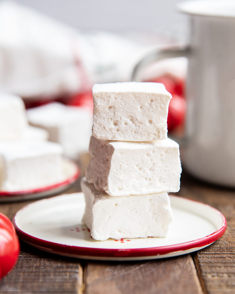 A stack of three square marshmallows on a plate.