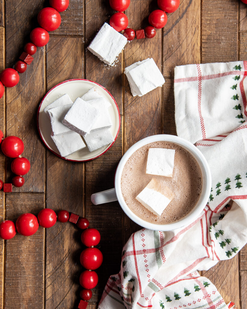 A cup of hot cocoa with two square marshmallows in it.