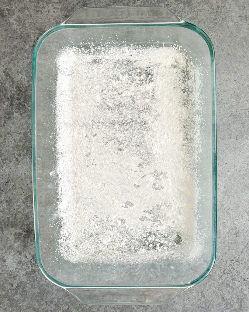 Powdered sugar duested in a glass rectangle pan.
