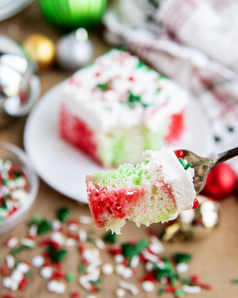 A forkful of Christmas Poke Cake with red and green jello coloring in it.