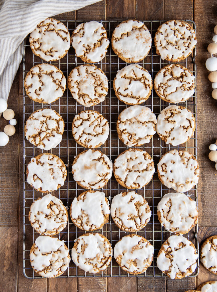 An above view of rows of iced gingerbread oatmeal cookies on a cooling rack.