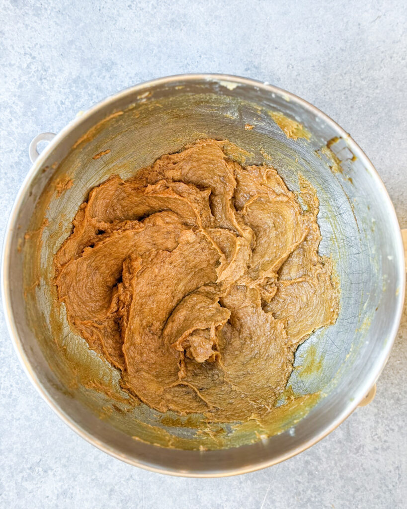 A wet molasses cookie dough starting to be made, with creamed butter, eggs, and molasses.