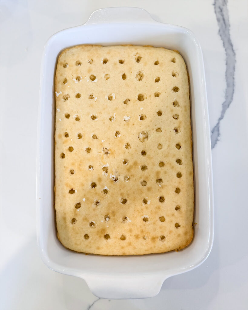 A cake in a white baking pan topped with holes all over.