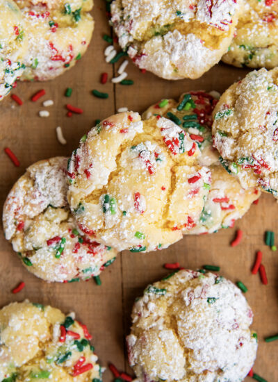 An above view of a pile of Christmas gooey butter cookies surrounded by Christmas sprinkles.