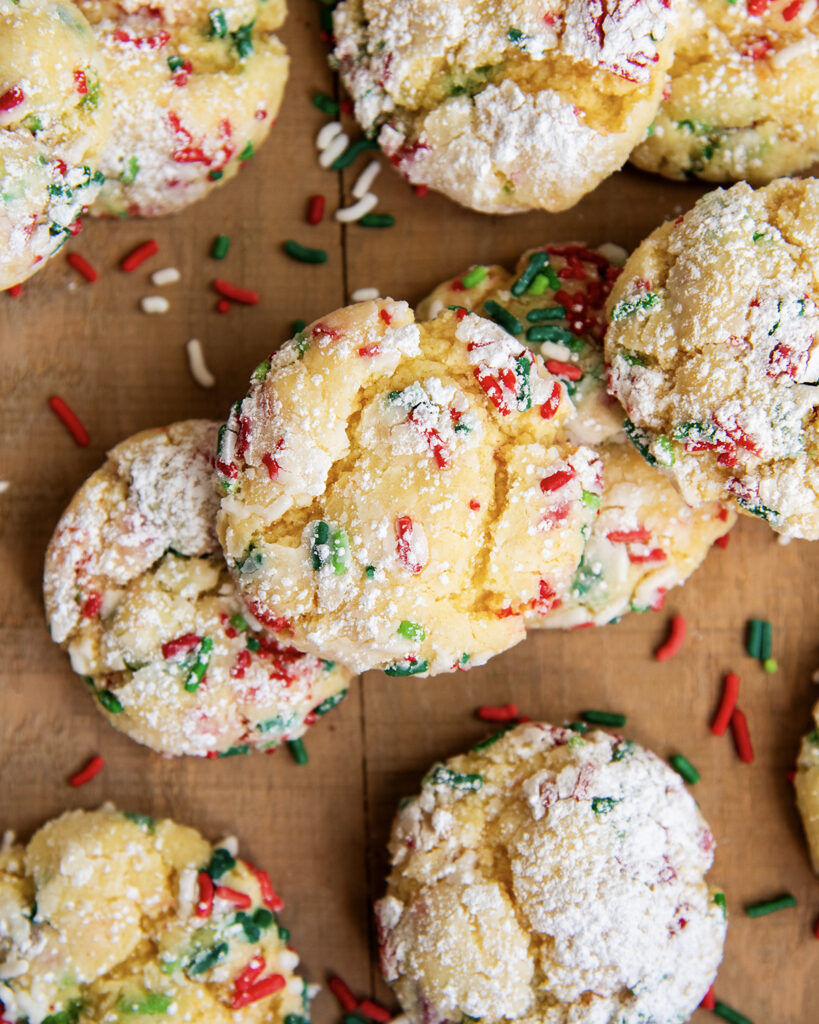 An above view of a pile of Christmas gooey butter cookies surrounded by Christmas sprinkles.