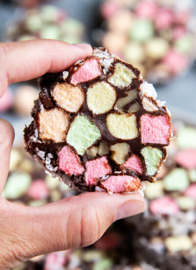 A hand holding a Church Window candy filled with colorful mini marshmallows, and walnuts coated in chocolate and coconut.