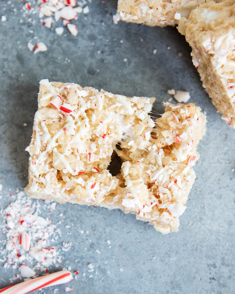 A gooey peppermint rice krispie treat split in the middle, and topped with candy cane pieces.