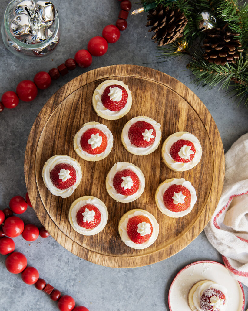 An above view of strawberry topped cheesecakes on a wooden board.